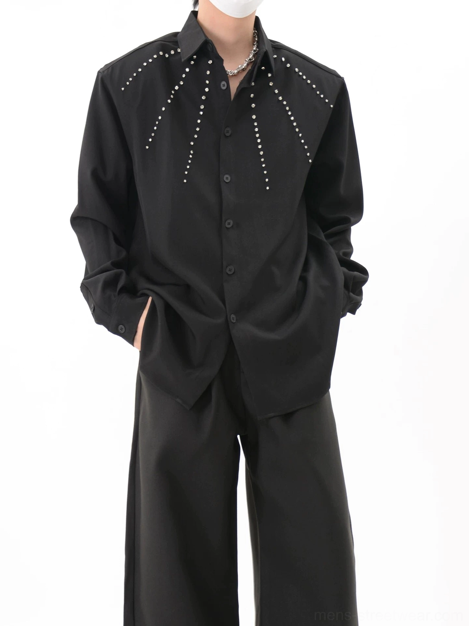 Black studded long-sleeve overshirt styled with a silver necklace and black wide-leg trousers in a full-body streetwear outfit