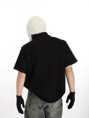 Black studded shoulder boxy streetwear T-shirt shown from the back with dropped shoulders, relaxed silhouette, short sleeves, and metallic shoulder details