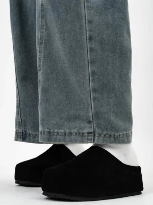 Black suede box toe clogs worn with white socks and loose washed blue jeans showing the thick minimalist platform sole