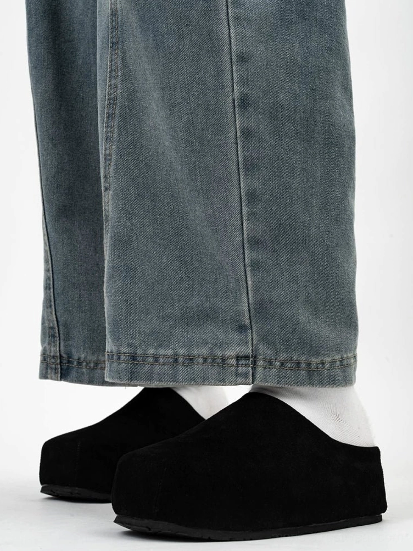 Black suede box toe clogs worn with white socks and loose washed blue jeans showing the thick minimalist platform sole