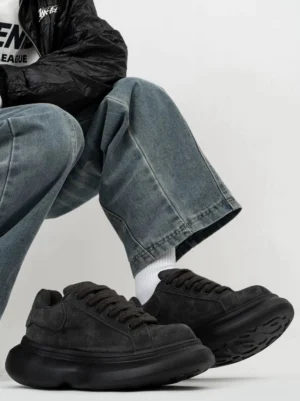 Black suede chunky platform sneakers worn with blue wide-leg jeans, black jacket, and white socks in a modern Seoul streetwear outfit