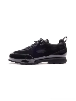 Black suede circular cutout chunky low-top sneakers shown in a clean side profile with glossy accents, lace-up closure, and layered streetwear outsole