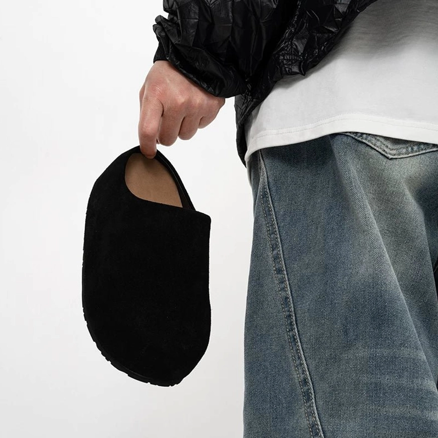 Black suede slip-on clog shown from the side rear with a streamlined laceless silhouette and chunky rubber outsole