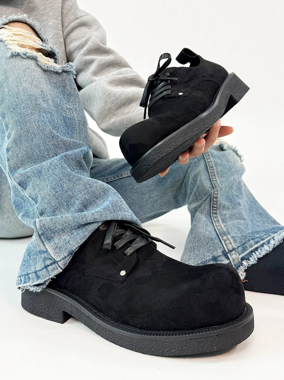 Black suede platform derby shoes styled with ripped blue jeans, rounded toe, lace-up closure, and matte chunky outsole