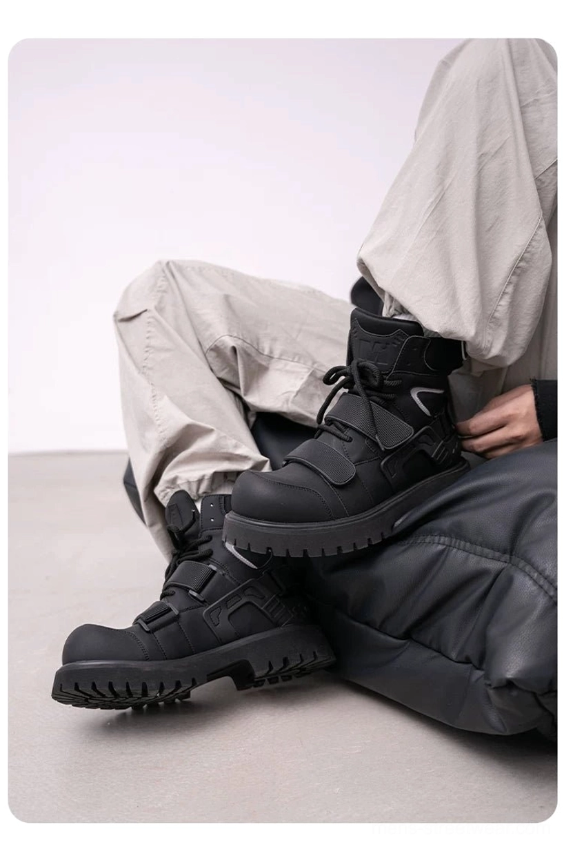 Low side view of a pair of black tactical work boots displaying layered harness details, matte PU leather, reflective accents, and rugged lug soles