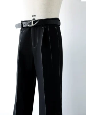 Close-up front view of black tailored flared trousers waist with white contrast stitching, structured waistband, leather belt, and metal buckle