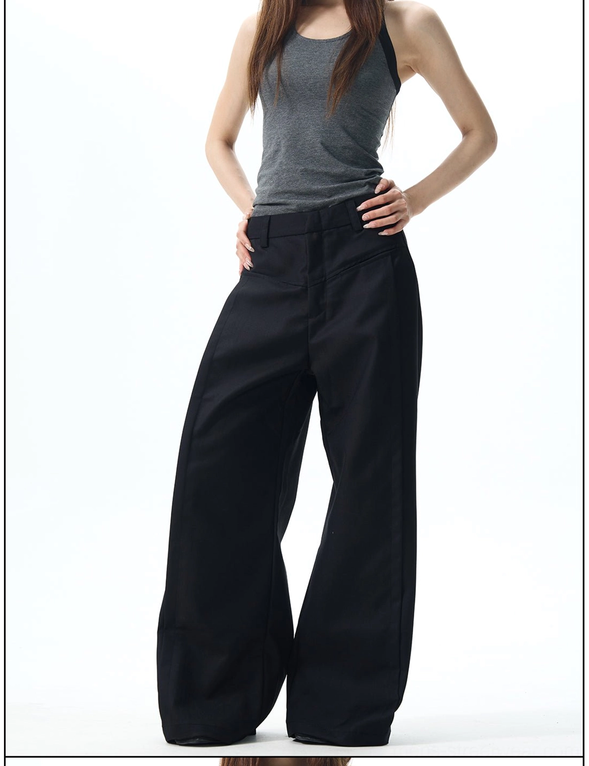 Side view of tailored black high-waisted wide-leg trousers with a fluid drape and matte minimalist finish