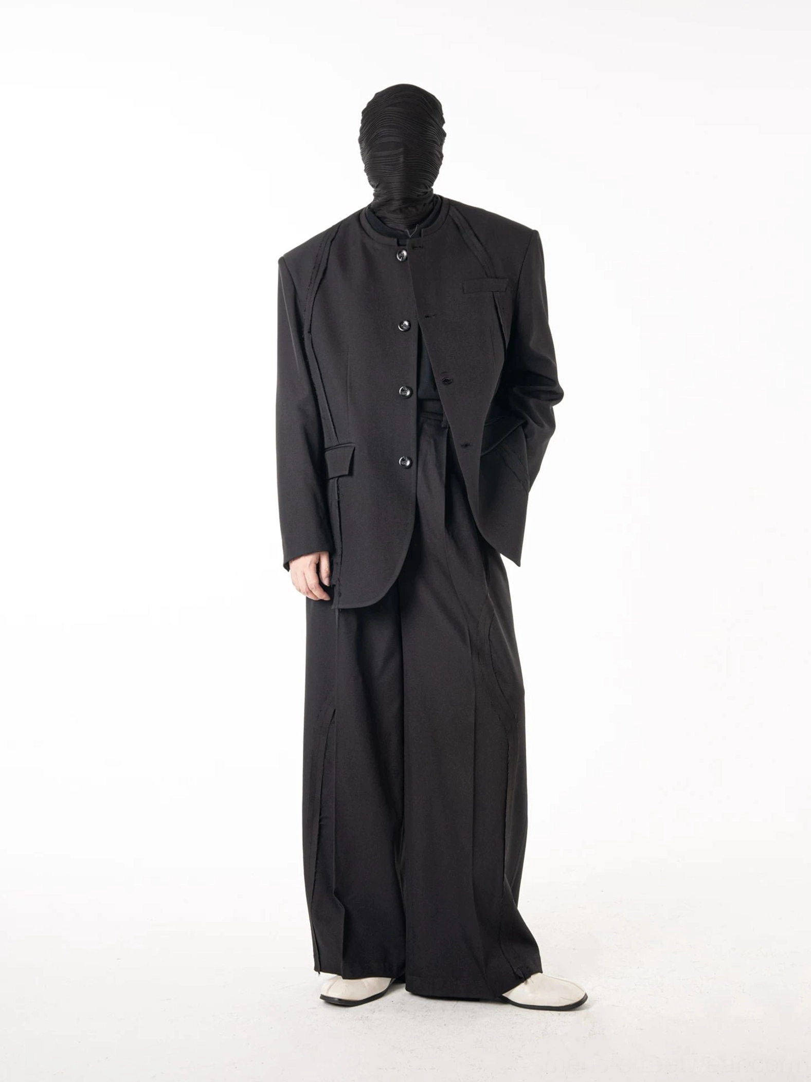 Side profile of an all-black tailored suit with relaxed blazer and wide-leg trousers inspired by Seoul streetwear