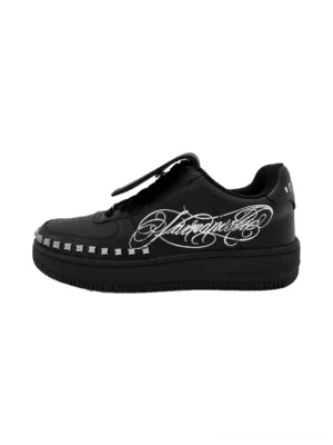 Black tattoo print foldover tongue chunky leather streetwear sneakers with silver rivet trim and cursive side graphic shown in left side profile