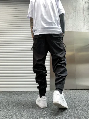Black tapered tech cargo joggers back view with utility pockets, adjustable drawstring waist and elastic cuffs