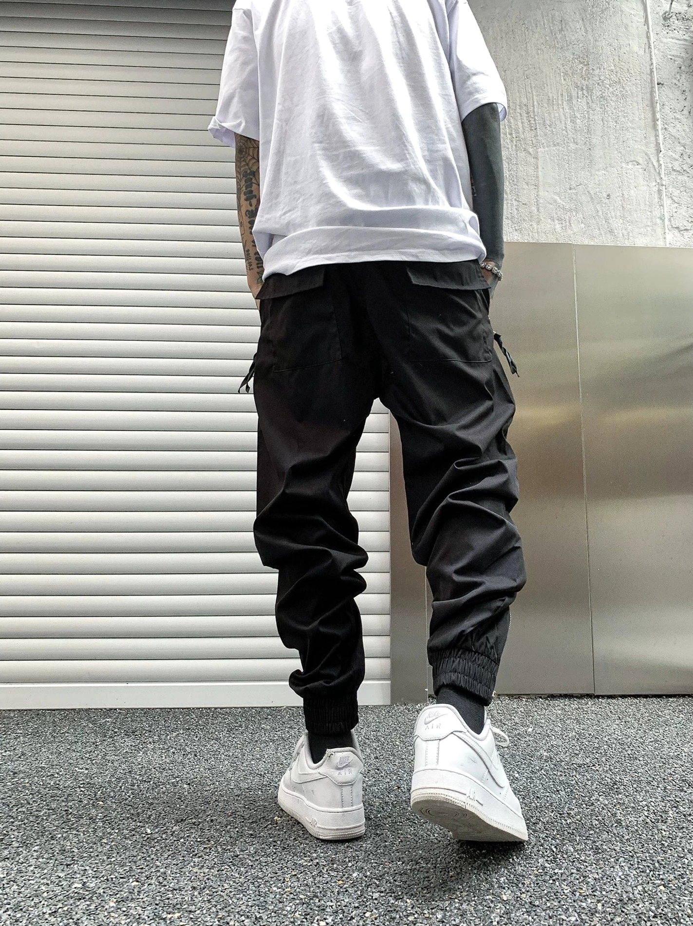 Black tapered tech cargo joggers back view with utility pockets, adjustable drawstring waist and elastic cuffs