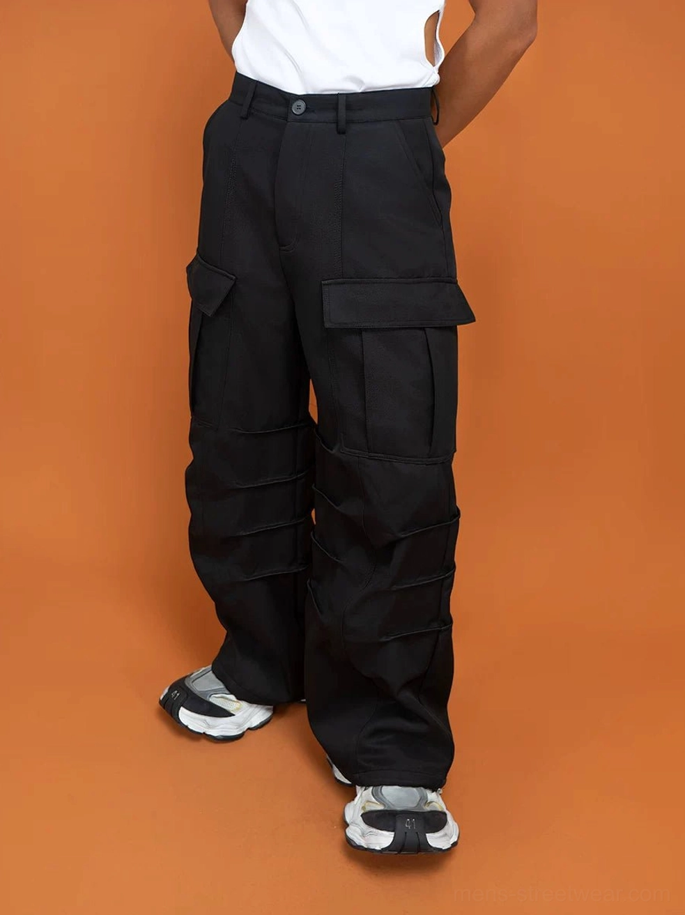 Black techwear cargo trousers shown from the front side angle with structured waistband, side flap pockets, and relaxed wide-leg cut