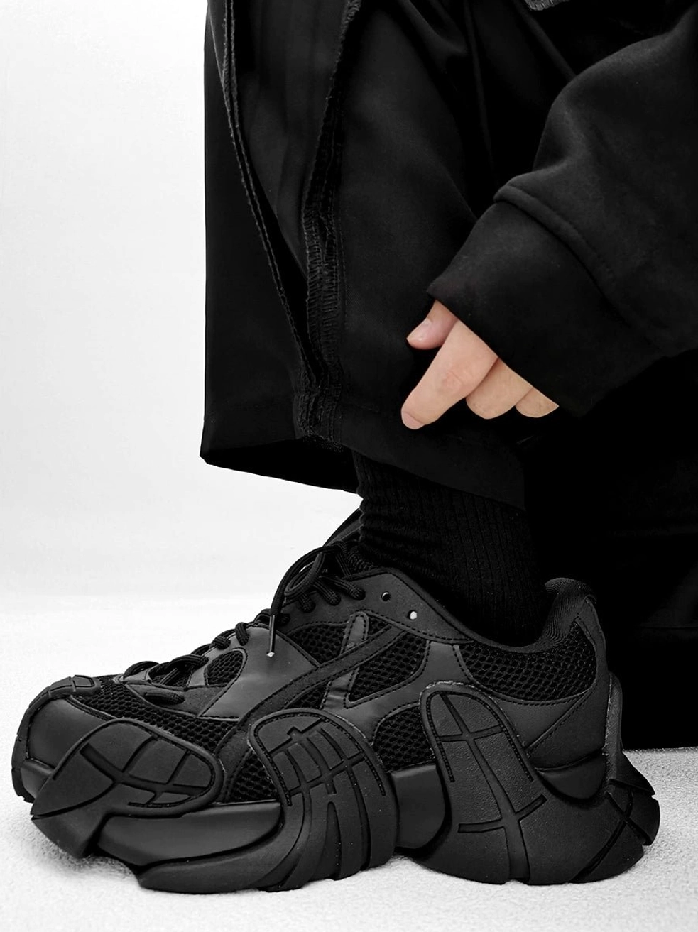 Black futuristic techwear chunky sneakers shown in side profile with mixed mesh and synthetic leather upper and sculpted rugged outsole