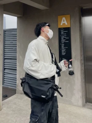 Side profile of black utility crossbody sling bag worn at the waist with adjustable webbing strap for urban techwear styling