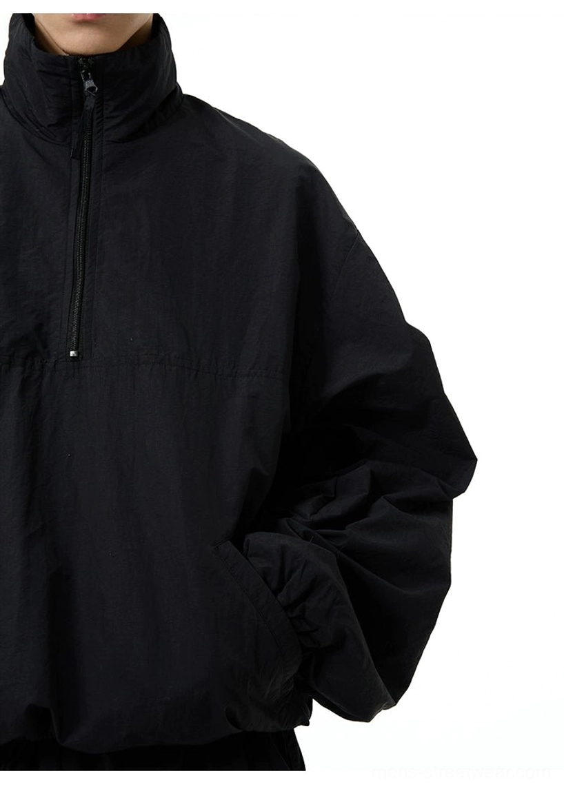 Close-up detail of the metal zipper pull, stand collar, and hidden side pockets on a black techwear windbreaker