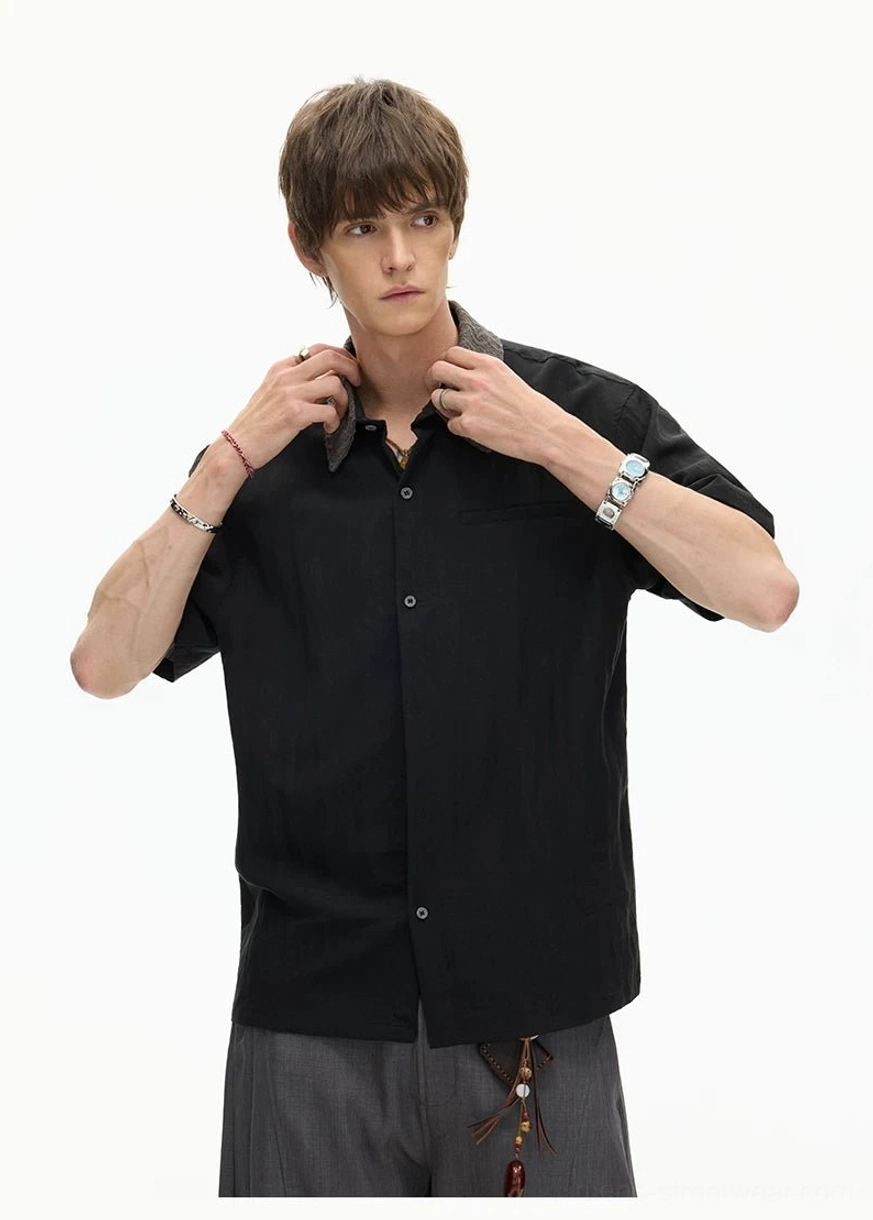Male model adjusting the grey textured collar of a black short sleeve streetwear button shirt