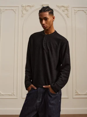 Black textured Henley knit shirt for men shown in a front three-quarter view with raised waffle ribbed fabric and long sleeves