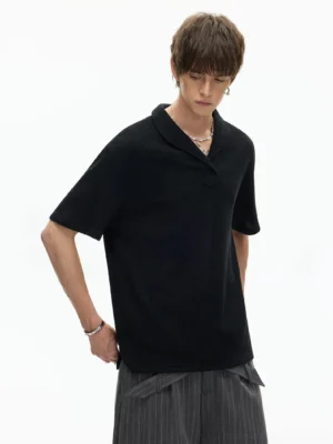 Black textured shawl collar knit polo tee with relaxed boxy fit styled with striped wide-leg trousers in a minimalist Korean streetwear studio look