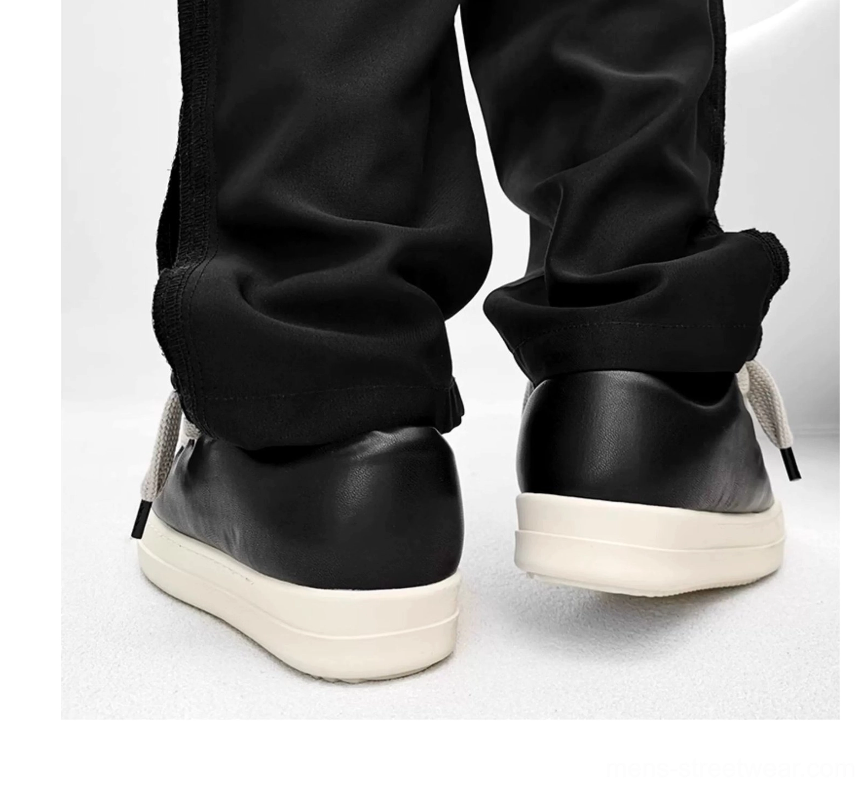 Rear view of black thick sole casual sneakers worn with cropped trousers, showing the smooth heel counter, clean stitching, and elevated platform outsole