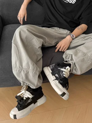 Black tie-dye double lace platform canvas sneakers worn with loose grey cargo pants in a streetwear outfit