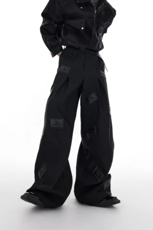 Black tonal logo patch wide-leg streetwear trousers worn in a full front studio look with cropped black jacket