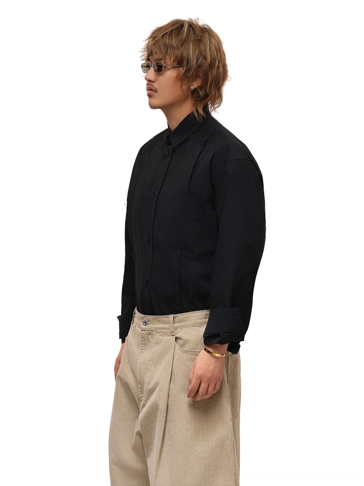 Side view of black tonal patchwork poplin shirt worn with beige trousers showing relaxed shoulders and concealed front pleat detail