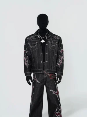 Front full body view of black tribal flame embroidered chain trim denim trucker jacket styled with matching wide leg jeans