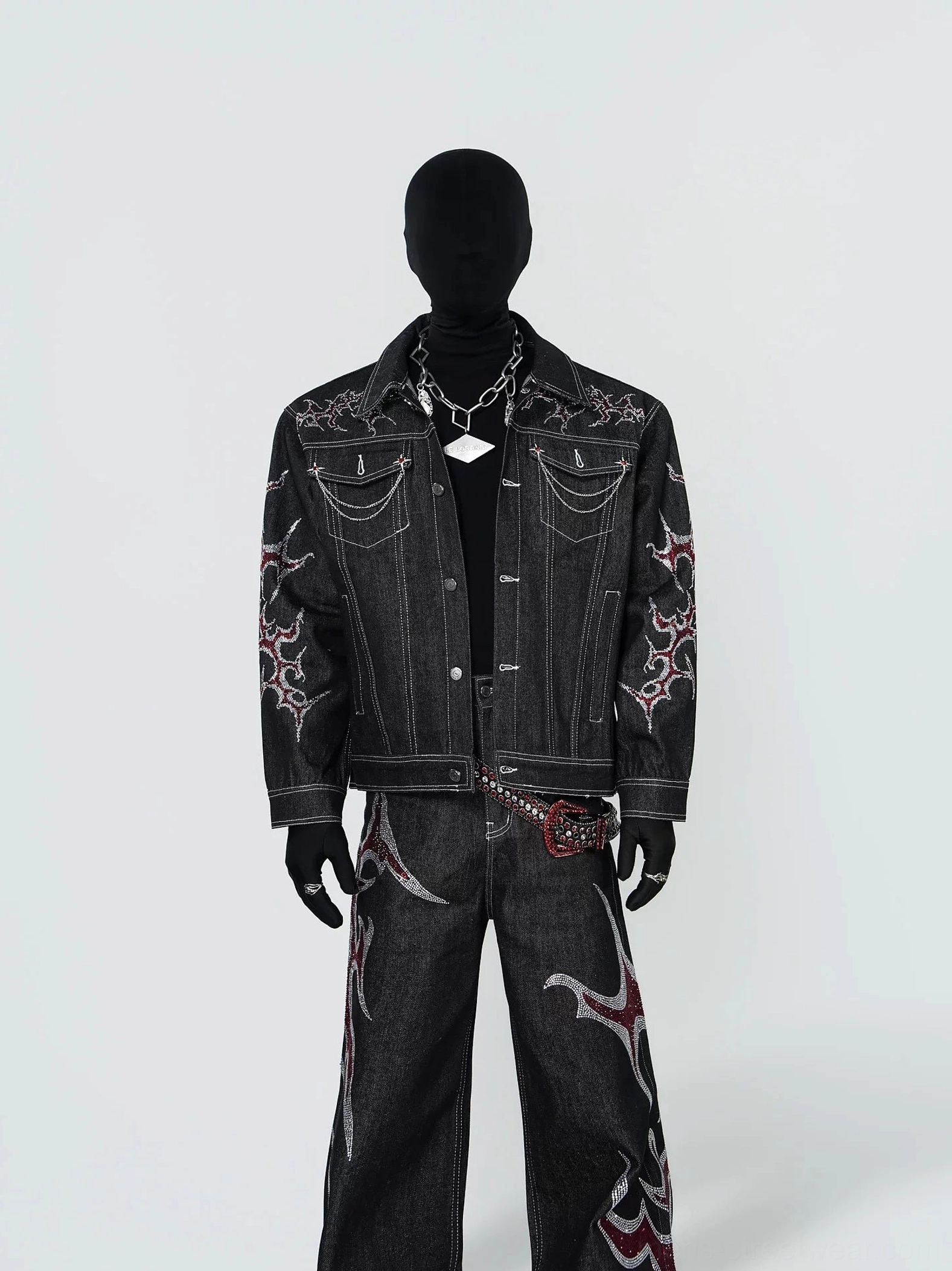 Front full body view of black tribal flame embroidered chain trim denim trucker jacket styled with matching wide leg jeans