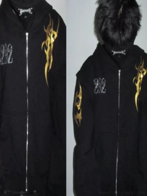 Model wearing black tribal flame faux fur hood zip hoodie with gold sleeve graphics and cropped streetwear fit