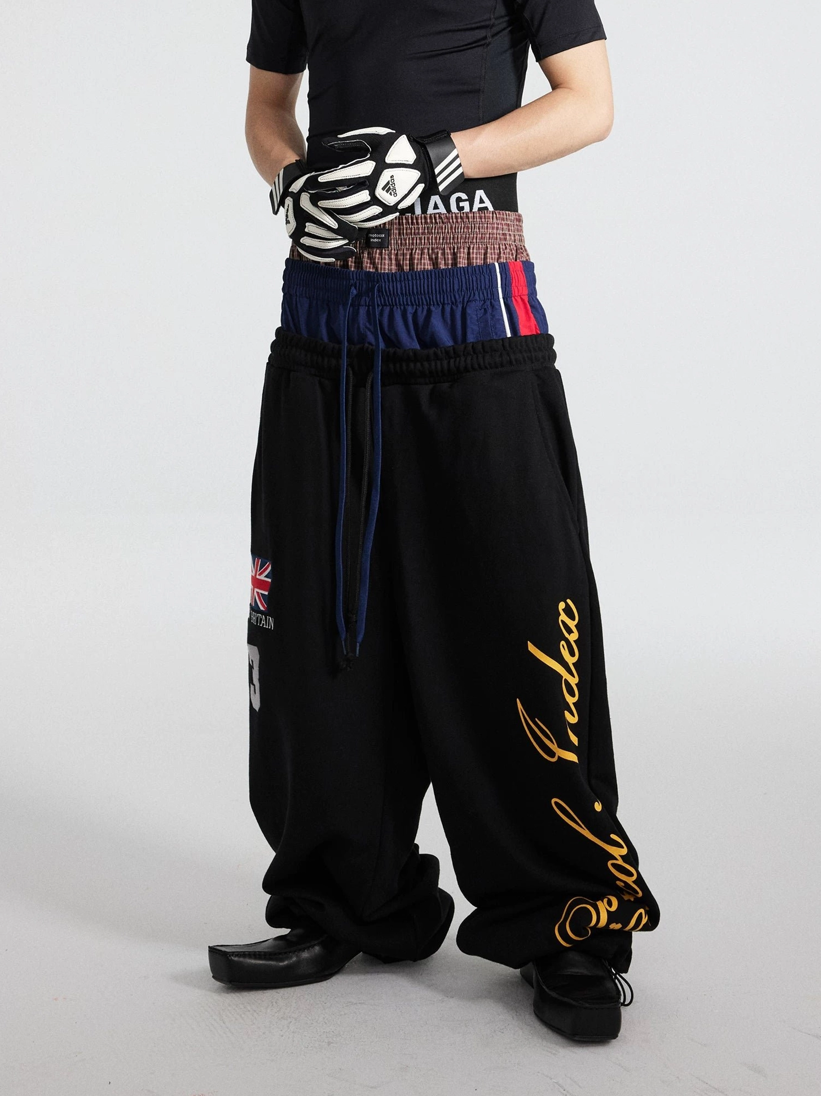 Black triple waist track flares with layered elastic waistband and oversized puddle leg streetwear outfit front view