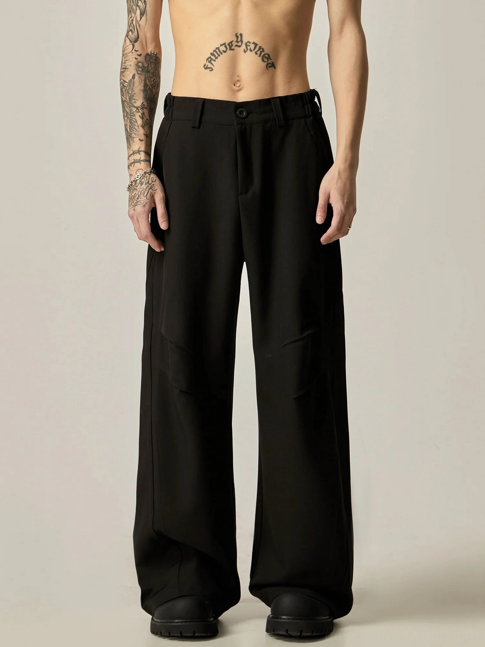 Black ultra-wide leg tailored trousers front full body view showing fluid oversized dress pant silhouette and button waist closure