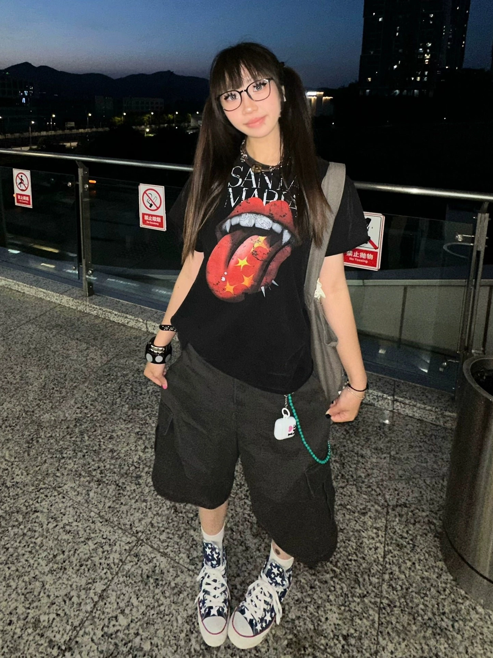 Female streetwear model wearing a black vampire lips and tongue graphic T-shirt with layered Korean fashion accessories