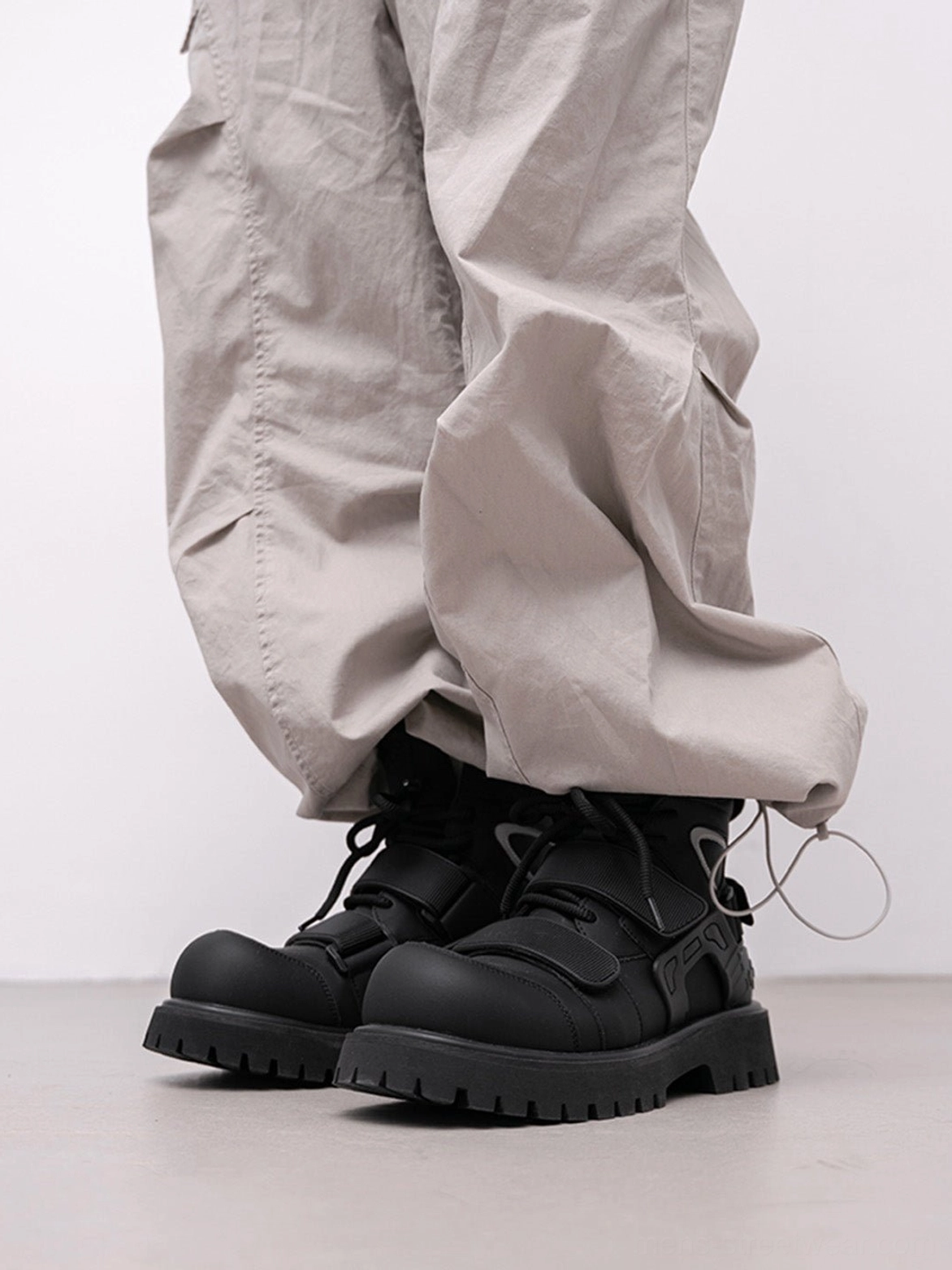 Front view of black Velcro strap lug sole moto combat boots with deep tread outsole and lace closure