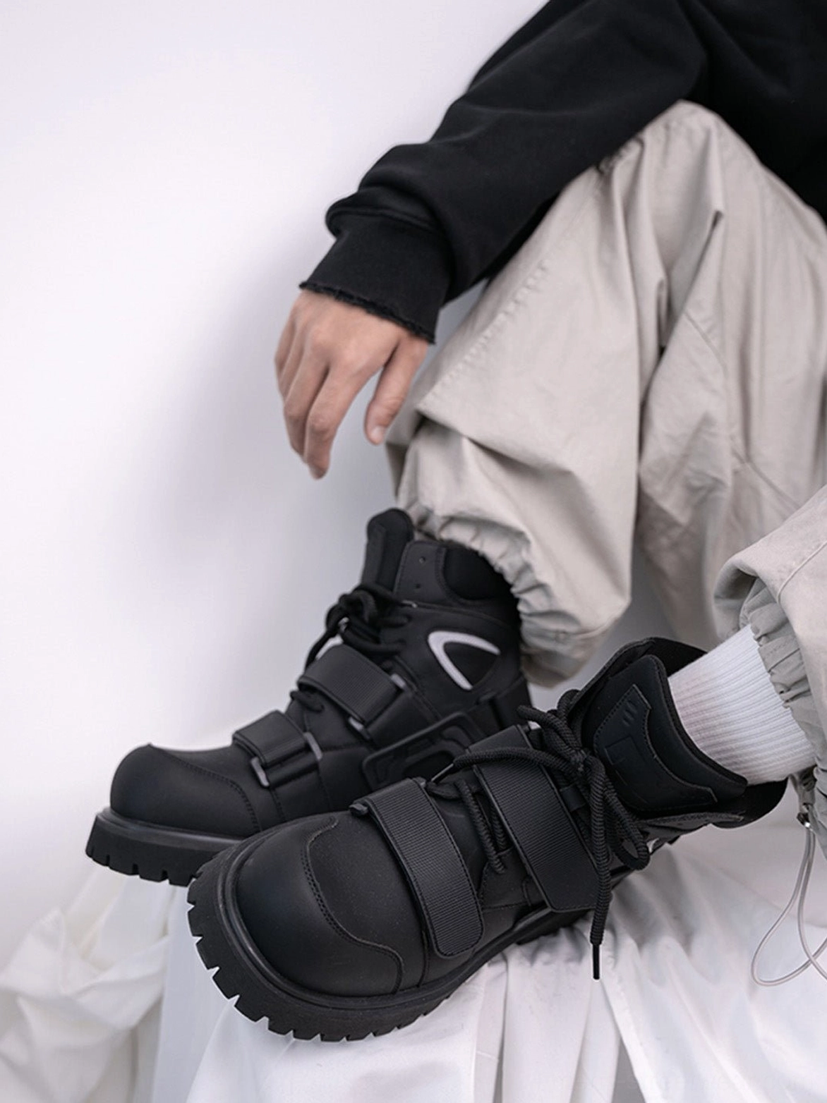 Black moto combat boots with Velcro straps silver-toned accents and chunky lug soles worn with cargo pants