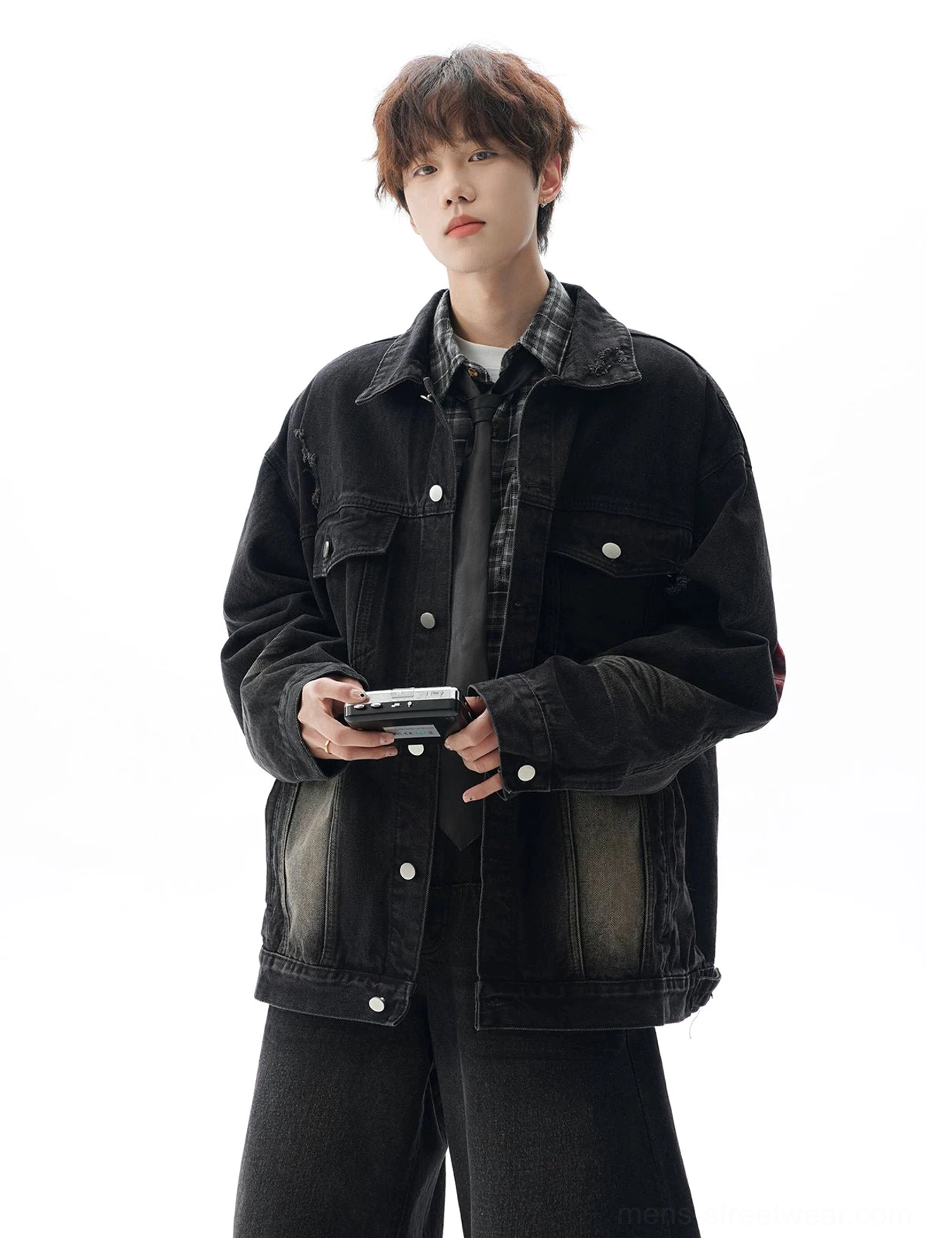 Black vintage distressed denim jacket with gradient fading, button closure, chest flap pockets, and layered urban streetwear outfit