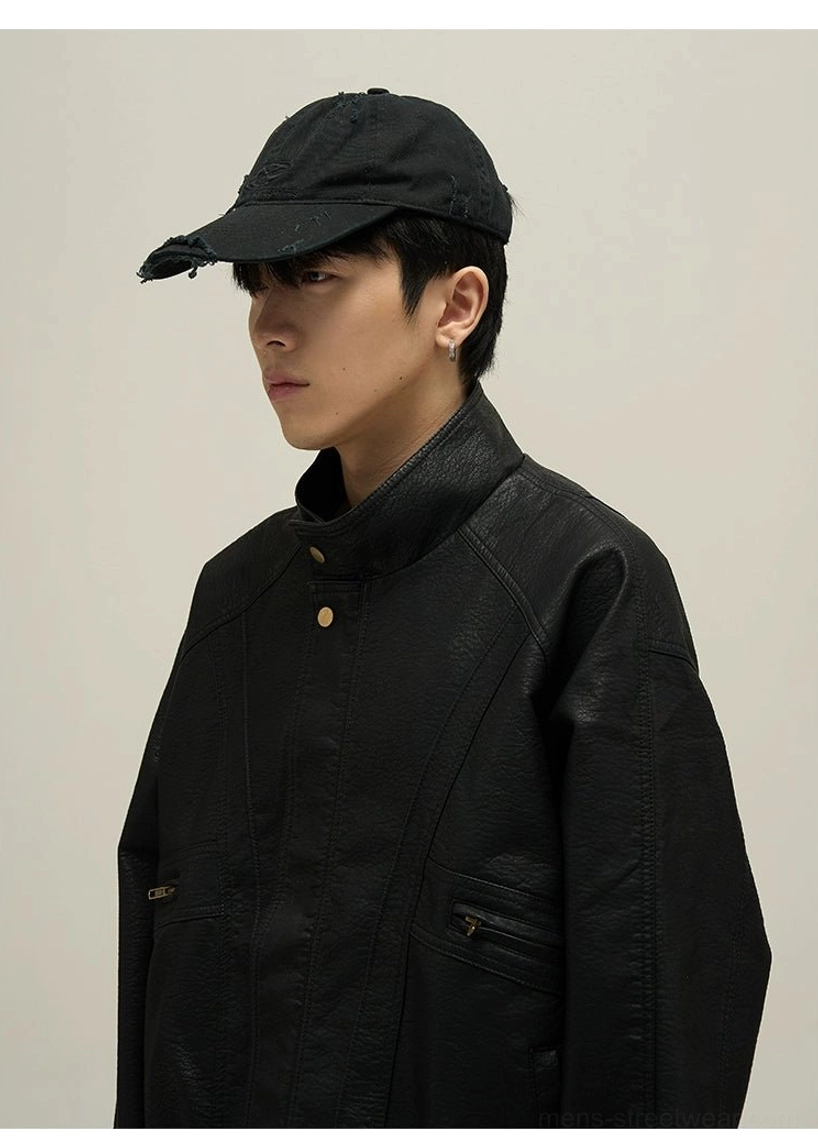 Close-up of black vintage faux leather bomber jacket with pebbled texture gold snap buttons and zip pockets