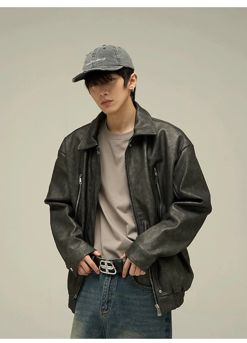 Close front view of a black vintage faux leather streetwear jacket showing the buttoned collar placket, textured finish, zipper pockets, and relaxed silhouette