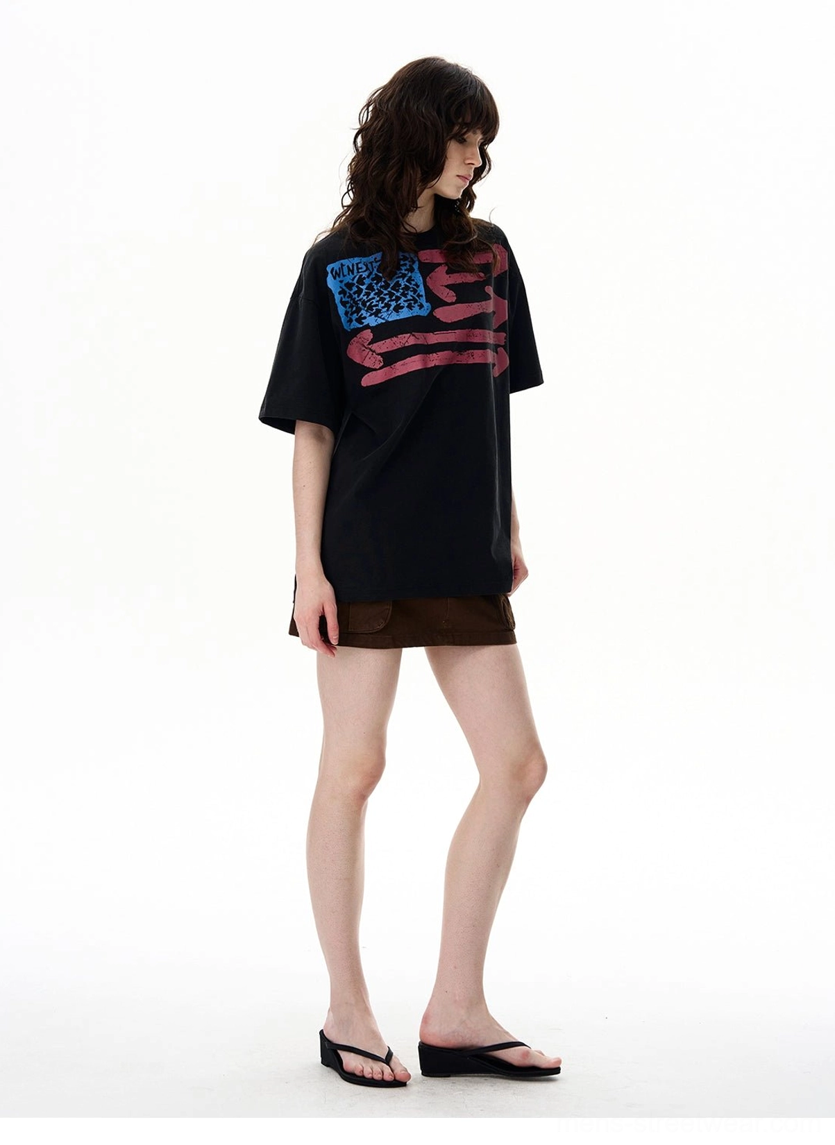 Three-quarter view of a black oversized vintage flag graphic T-shirt with distressed chest print and loose streetwear silhouette