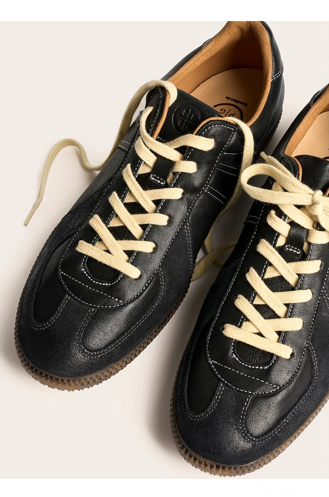 Pair of black vintage leather sneakers with clean uppers and loosely tied off-white laces