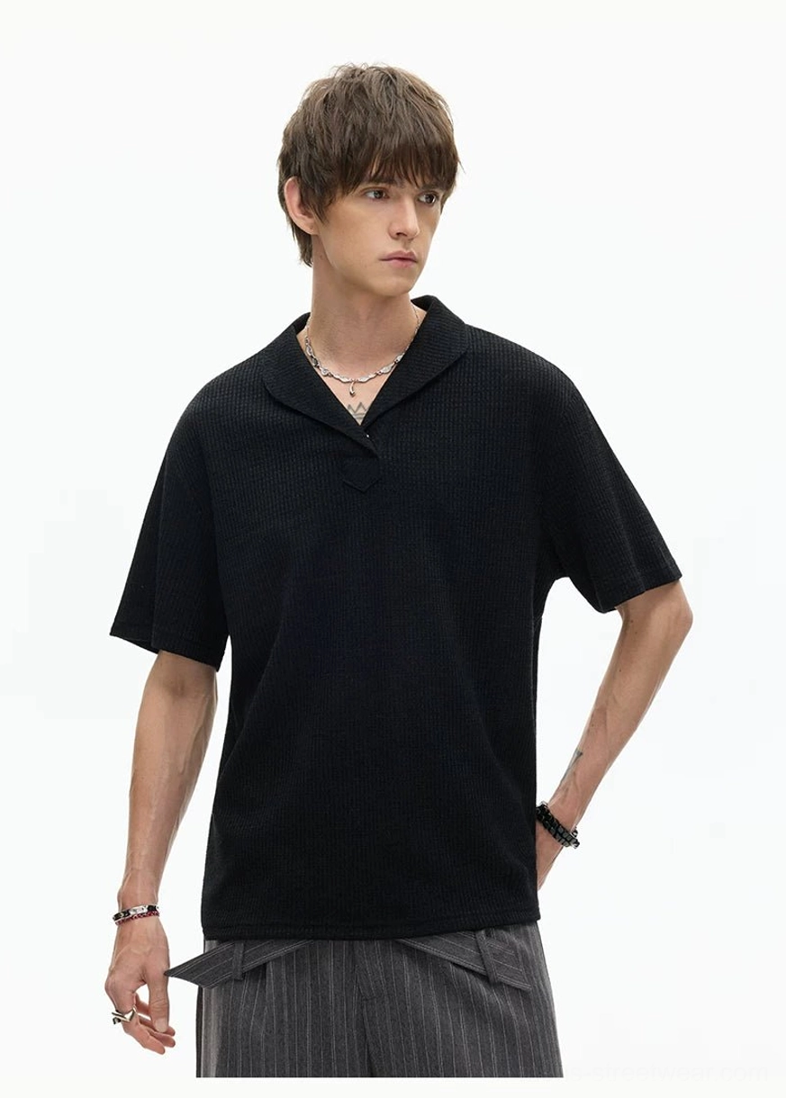 Black waffle textured shawl collar knit polo tee in three-quarter view styled with striped wide-leg trousers for contemporary Seoul fashion