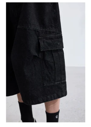 Black washed denim wide-leg cargo capri shorts side close-up showing oversized flap utility pocket durable denim and loose cropped leg