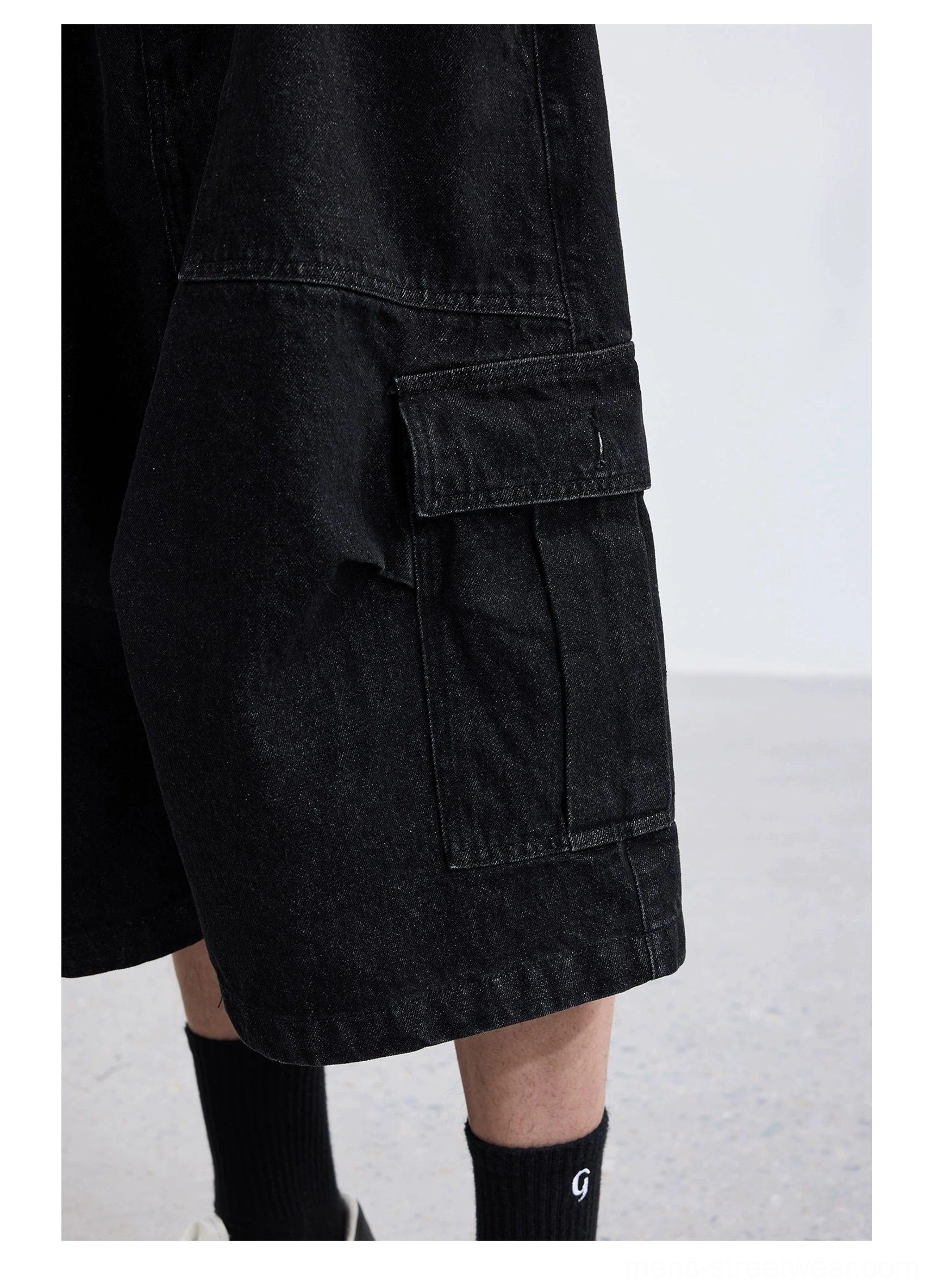 Black washed denim wide-leg cargo capri shorts side close-up showing oversized flap utility pocket durable denim and loose cropped leg
