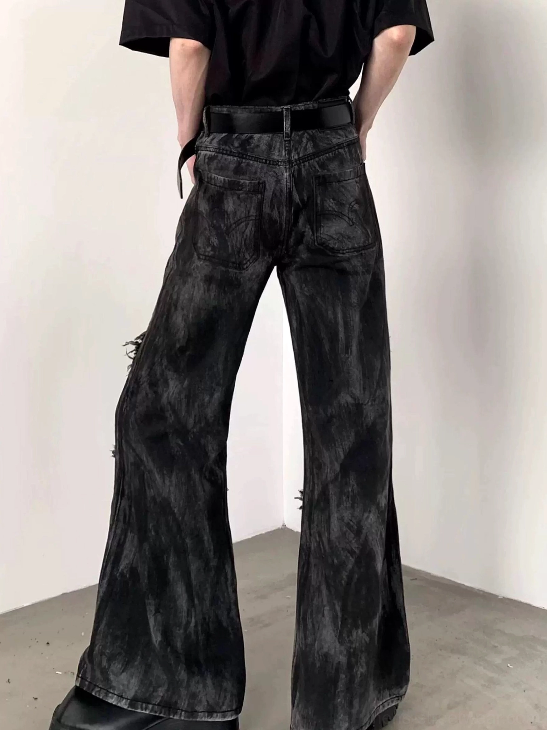 Back view of black washed flared jeans with wide flare legs, standard back pockets, and distressed vintage denim streetwear design