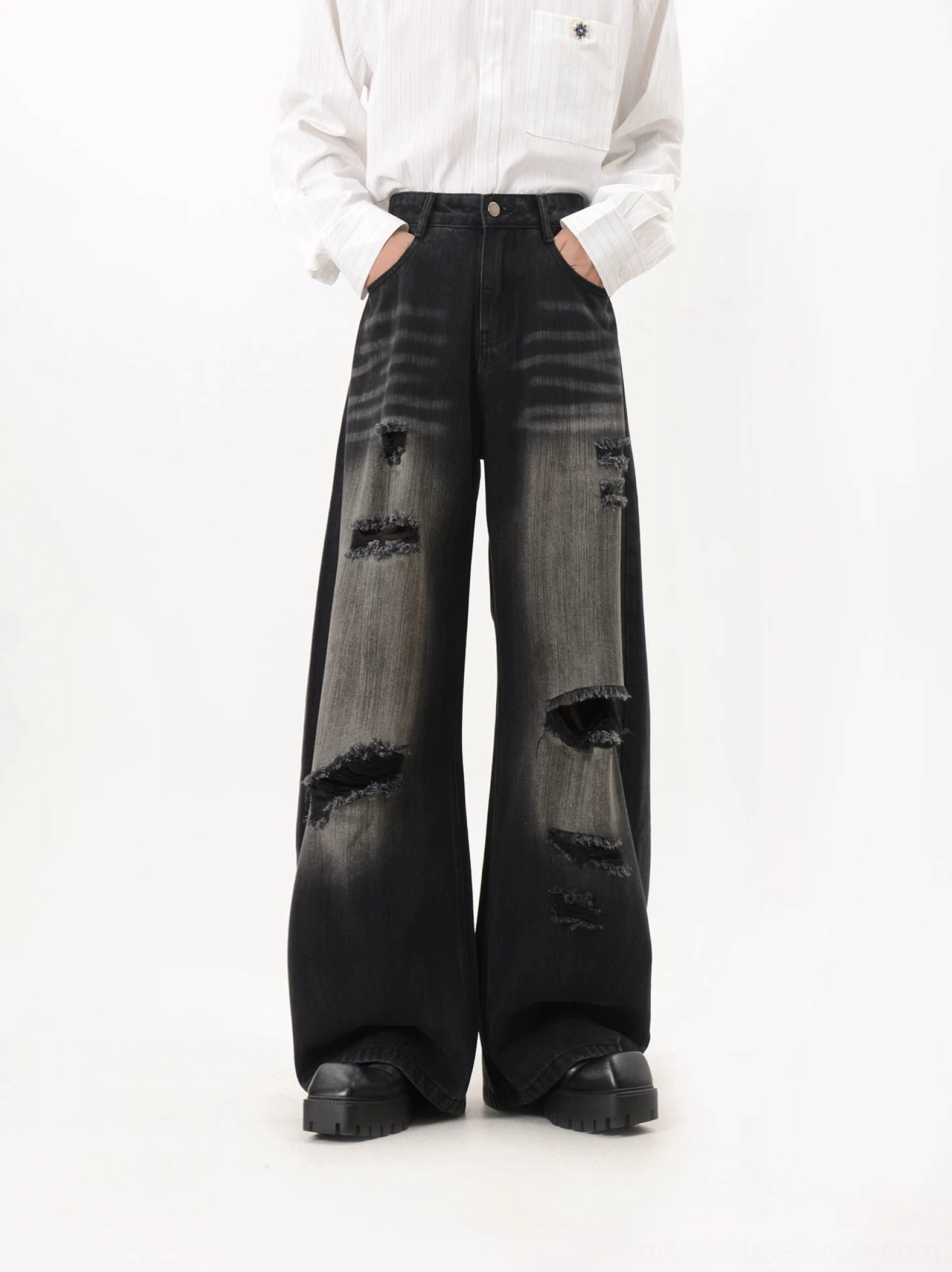 Front detail view of black washed heavily ripped wide leg jeans featuring button waist closure, whisker wash, and raw frayed holes