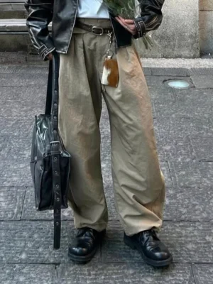 Model wearing black washed horsehide derby shoes with a leather jacket, high-waisted wide-leg khaki pants, and leather tote on an urban street