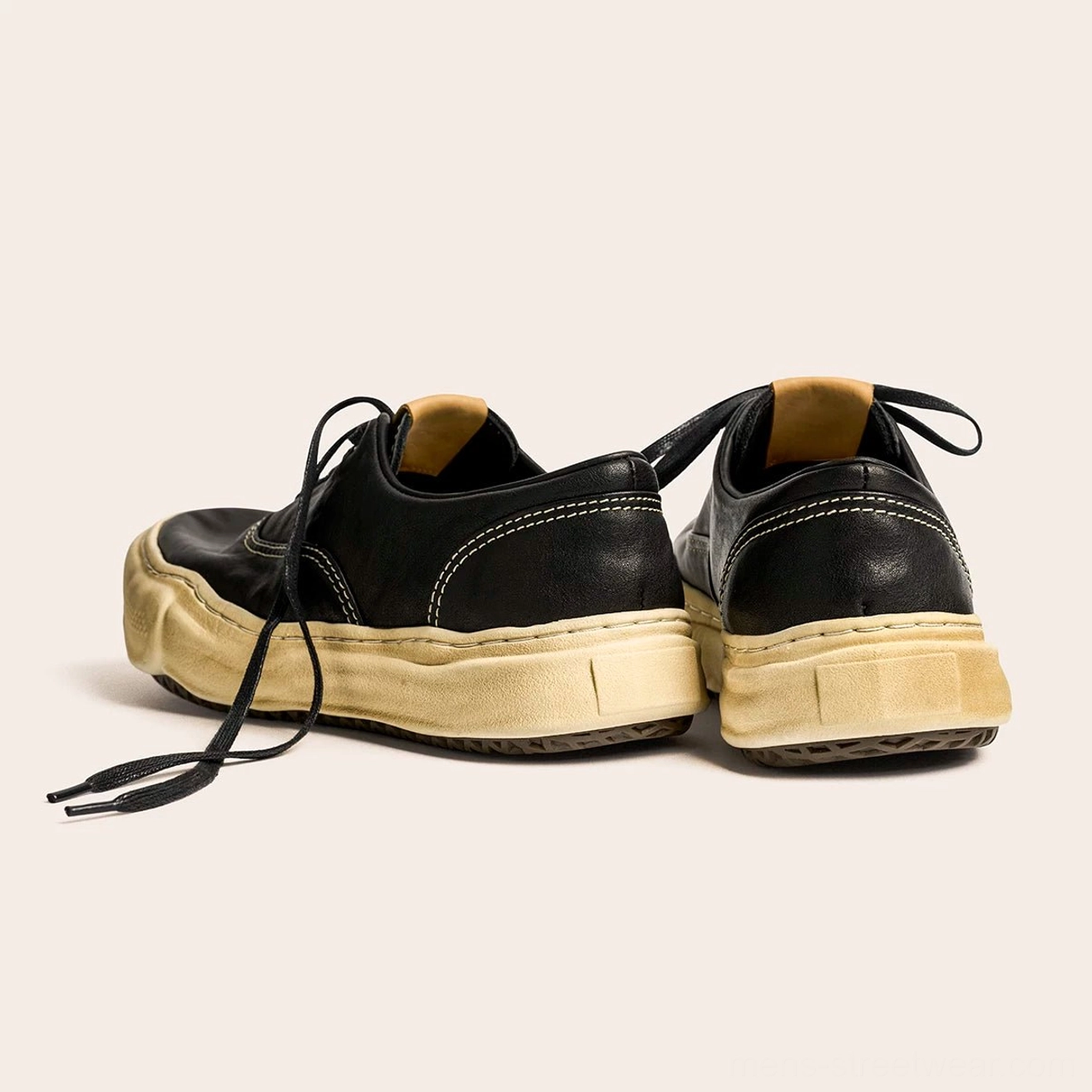 Rear three-quarter view of black washed leather streetwear sneakers with contrast stitching, exposed leather insole, and weathered thick retro sole