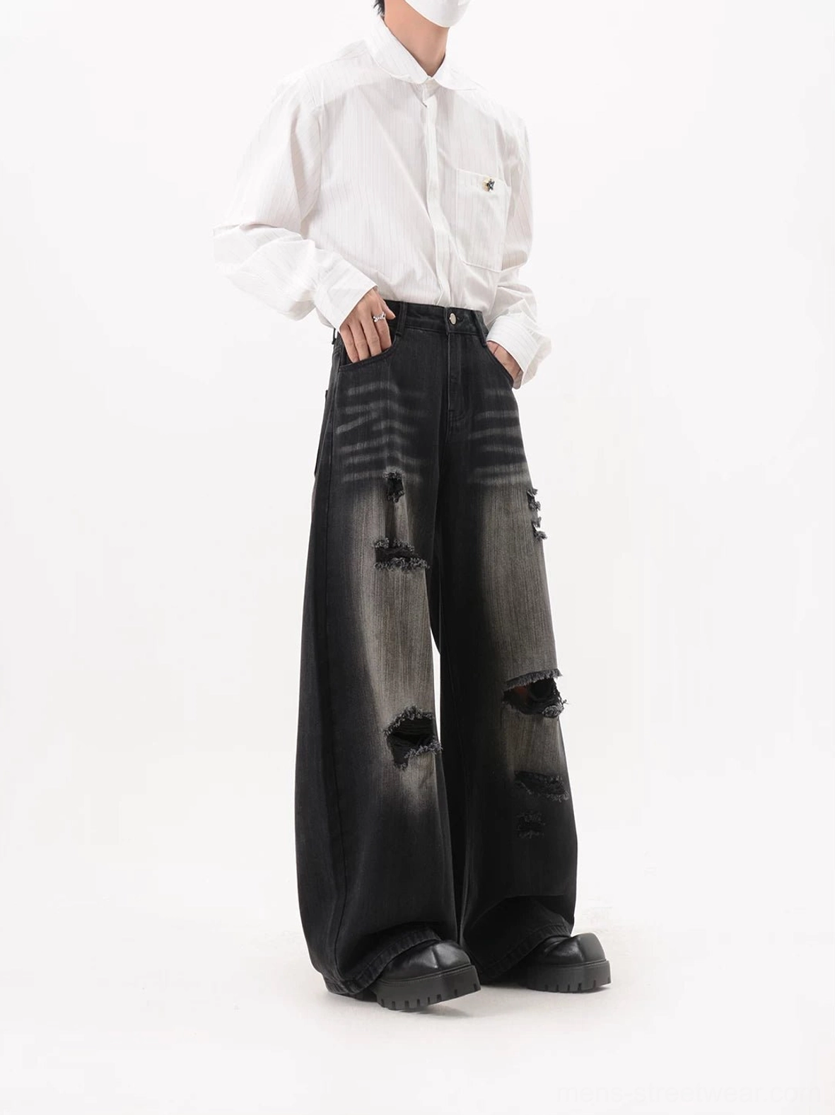 Side front view of black washed ripped wide leg jeans with whisker fading, loose streetwear fit, and distressed thigh panels
