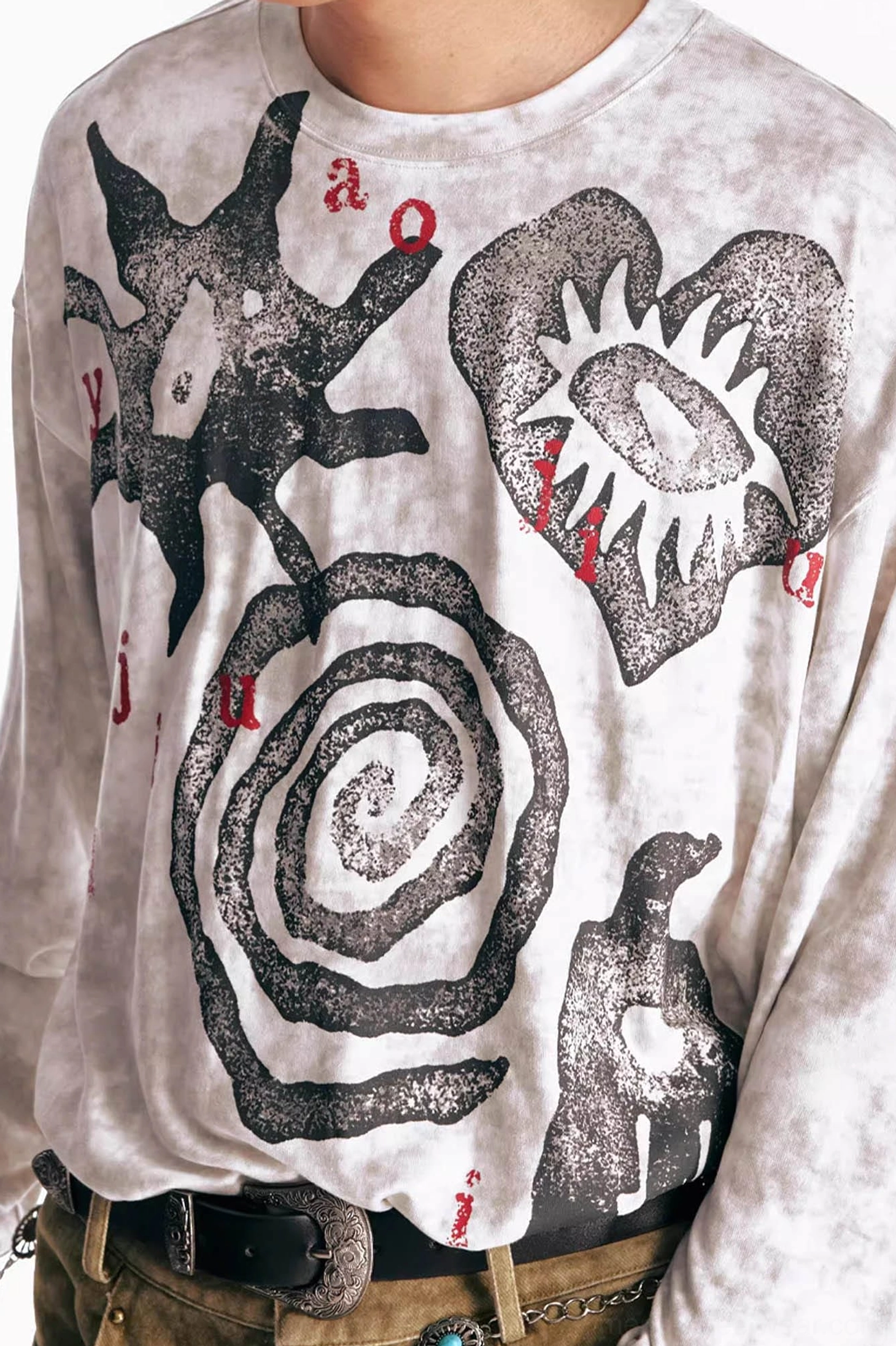 Close-up of black washed tribal graphic long sleeve tee showing distressed black artwork and faded red lettering