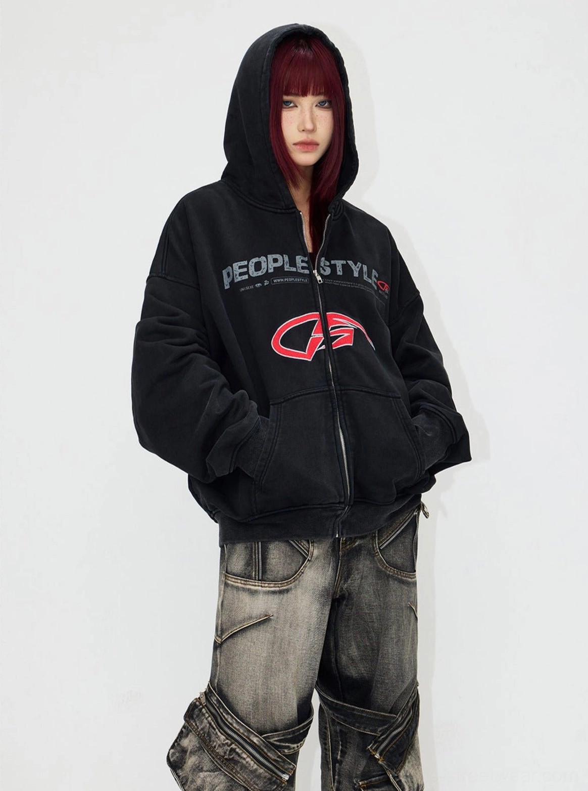 Front view of a black washed vintage distressed zip-up hooded jacket with red chest graphic detail and cargo denim styling