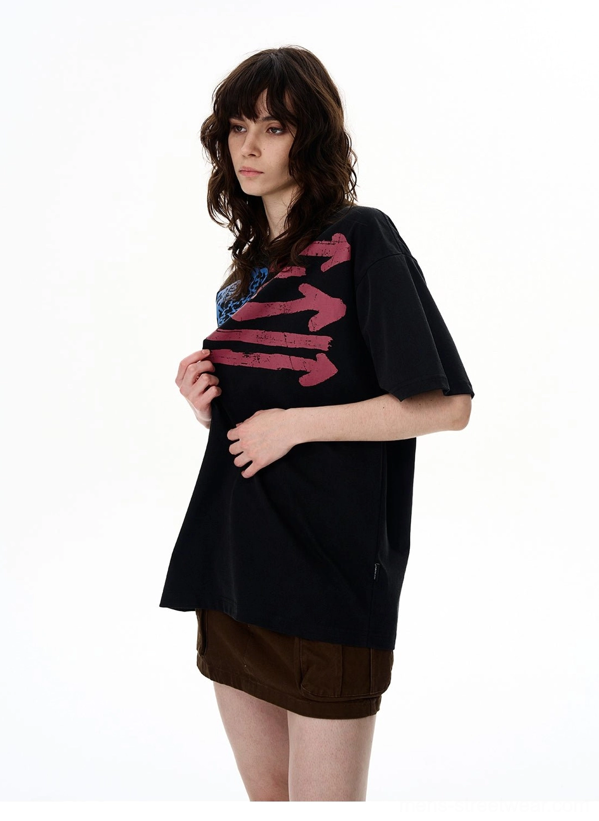 Side view of a black washed vintage flag graphic oversized T-shirt styled with a brown mini skirt in a relaxed streetwear look